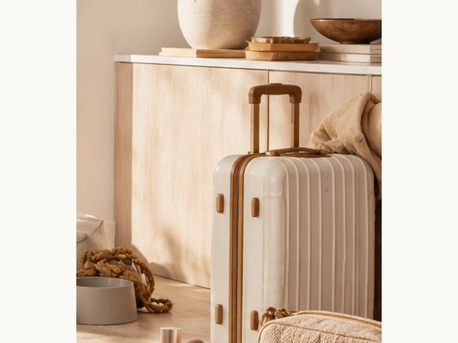 A refined hard-shell suitcase and travel accessories in a warm neutral interior